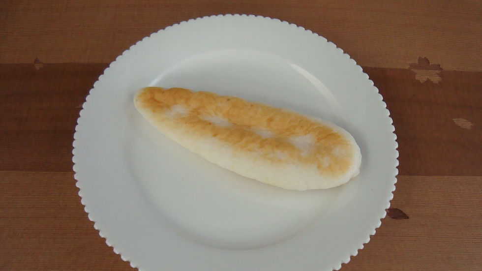 縁飾りのある白い皿に乗せた焼き色のついた笹かまぼこ
