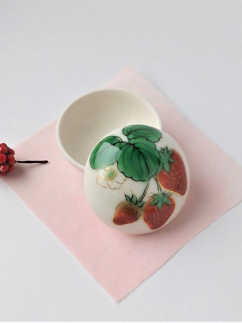 苺と花を描いた白い丸い蓋物(ボンボニエール)の蓋を外し、桃色の和紙の上に置いた様子