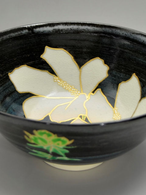 黒釉の内側に白い木槿の花を描いた茶碗、外側に緑の葉