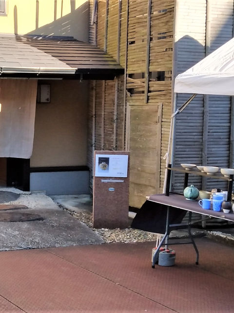 郷まつりで屋外展示された陶器の器と暖簾のかかった建物