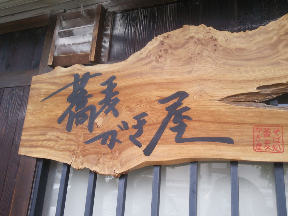 木の一枚板に「蕎麦がき屋」と書かれた看板