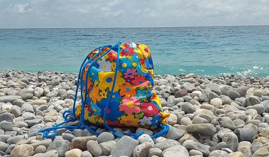 Designer backpack with floral print by Alex Doll by the seaside.