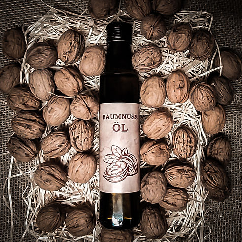 Eine 2.5dl Flasche mit Baumnussöl, inmitten von Nüssen auf Stroh gebettet.