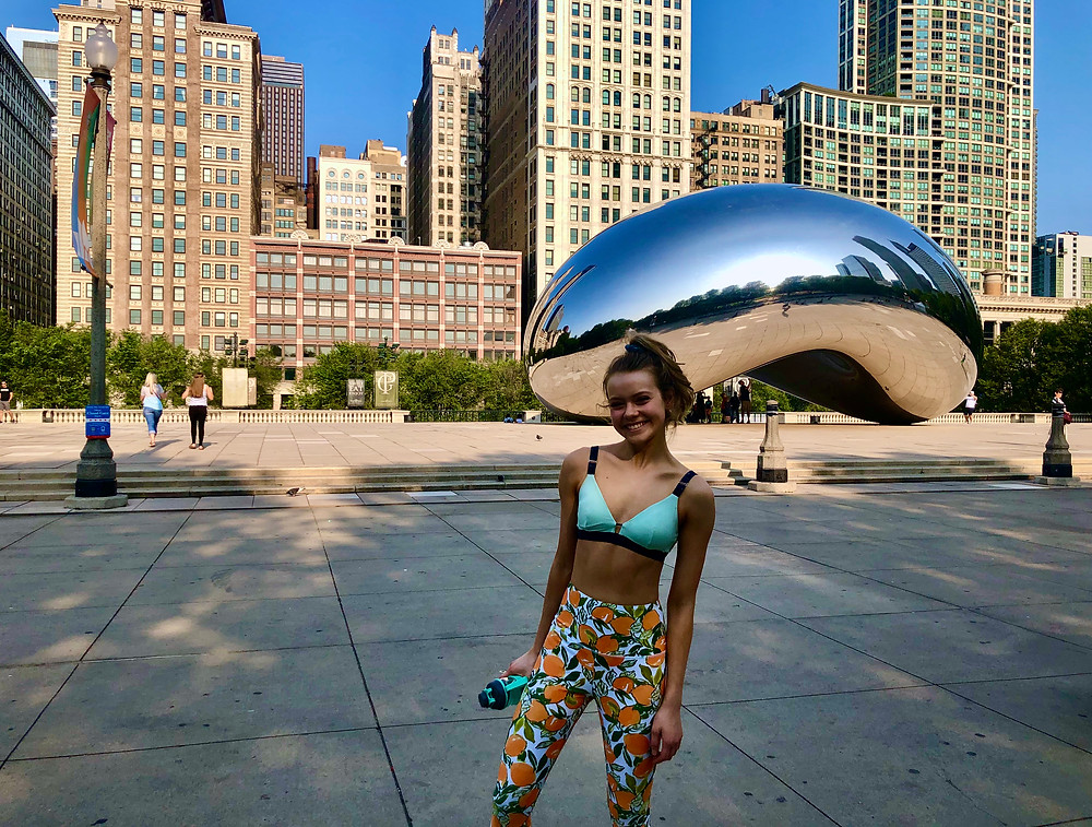 Girl in colorful leggings standing and smiling in front of the Bean sculpture in Chicago