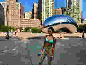 Girl in colorful leggings standing and smiling in front of the Bean sculpture in Chicago