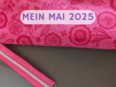 Pink gemusterter Stoff mit floralen Motiven, darunter ein passender Reißverschluss in Pink auf grauem Untergrund. Im oberen Bereich steht in lila Schrift auf einem transparenten Banner: „Mein Mai 2025“ – ein Rückblick auf den kreativen Monat einer Handmade-Taschenmacherin.