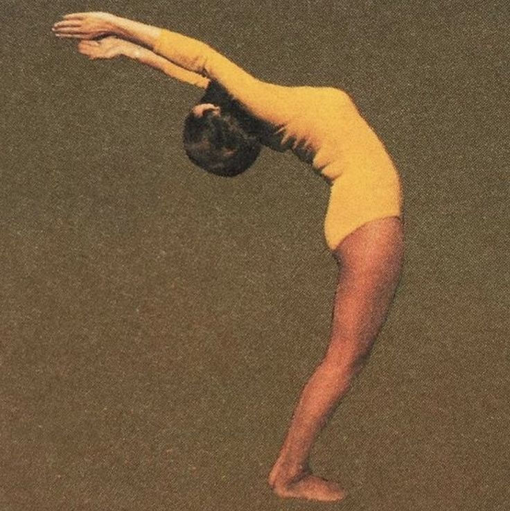 Woman in a yellow leotard doing a deep backbend gymnastics pose against a plain brown background