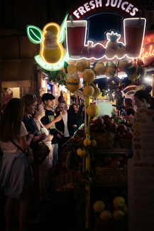 Neon lit fresh juice stall on Via San Cesareo at night with tourists queuing, Sorrento, Italy