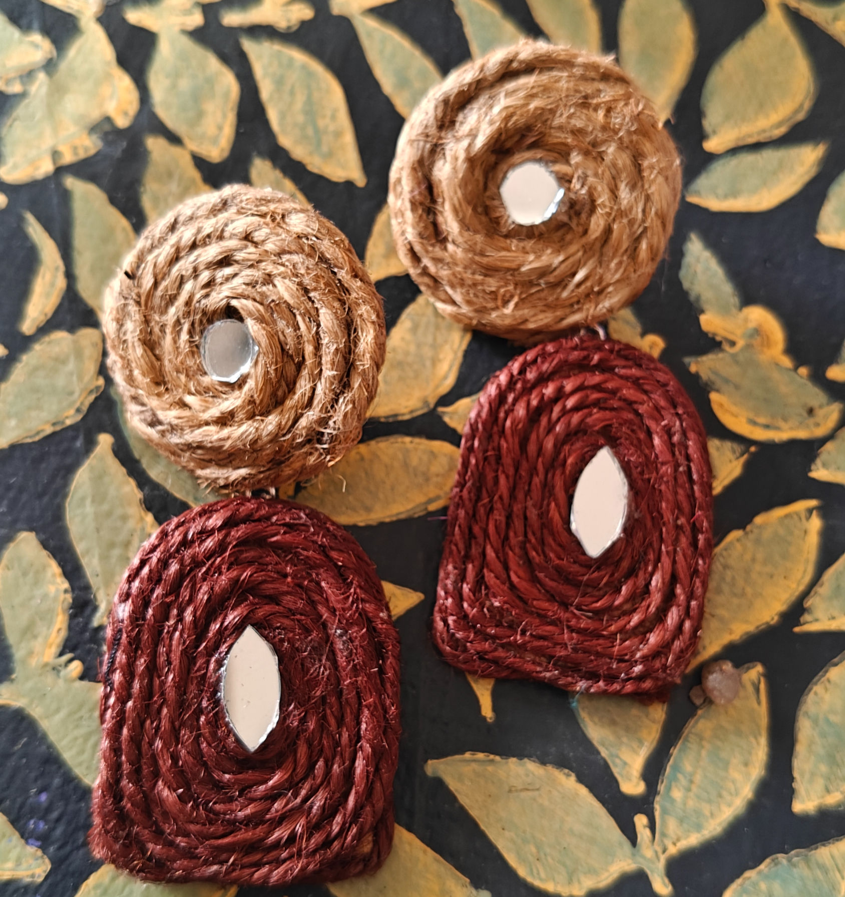 Woven earrings with tan spirals and maroon drops.