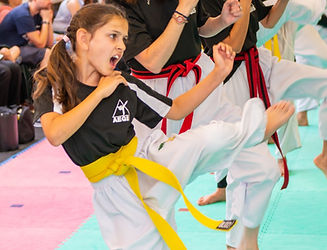 Confident child throwing kick in a martial arts class