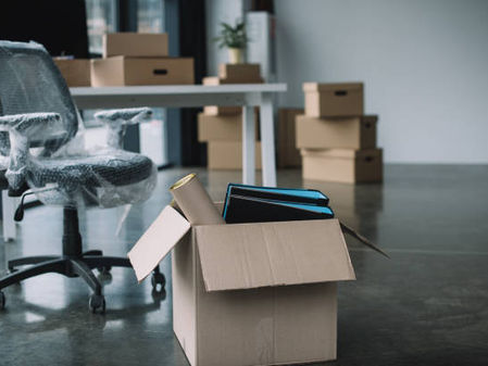 Open office with packed boxes and wrapped chair ready for moving.