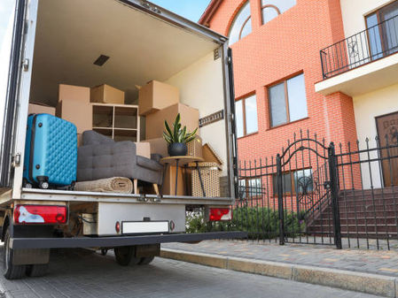 Moving truck loaded with furniture and boxes outside a house.