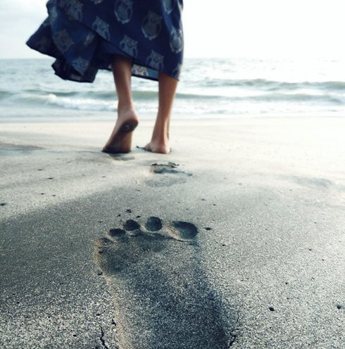 close up of woman walking on the beach with foot print