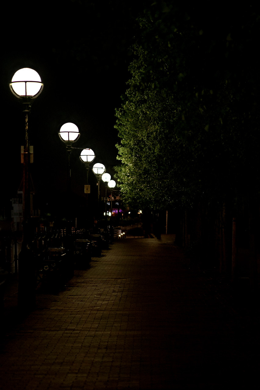 The walk way alongside Salford Quays at night with lighting and trees
