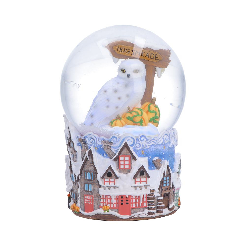 This officially licensed Harry Potter Hogsmeade Village Snow Globe captures the charm of the iconic wizarding village, featuring Hedwig perched alongside the Hogsmeade sign inside a snowy blue globe. Detailed houses wrap around the base, while pumpkins and finely sculpted elements add extra character. Cast in resin and expertly hand-painted, it comes packaged in a themed gift box, making it perfect for collectors and fans alike. A magical decor piece that brings the cosy, wintry spirit of Hogsmeade into your home.