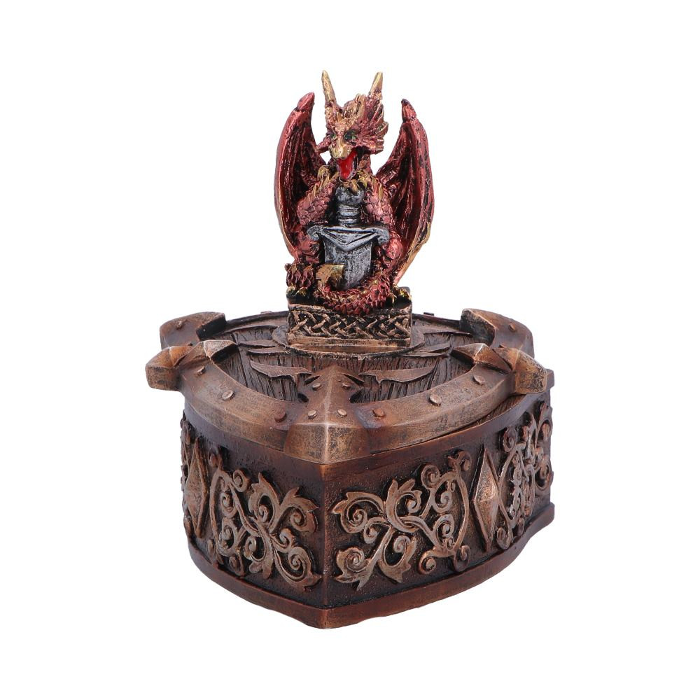The Hoard Defender Box is an originally designed dragon trinket box from Nemesis Now, featuring a fierce red dragon standing proudly atop a shield-shaped box while gripping a sword. Standing 10.4cm tall, the piece is rich in detail, from the vivid red dragon to the intricate fantasy engravings and sharp accents decorating the box beneath it. The removable lid reveals a small compartment perfect for storing jewellery, coins, and treasured keepsakes, while the hand-painted finish combines dark brown and metallic-like tones that contrast strikingly with the bold red dragon. Securely packaged for protection, this decorative storage piece is ideal for fantasy collectors, dragon enthusiasts, and lovers of mythical decor who want their small treasures guarded by a powerful dragon.