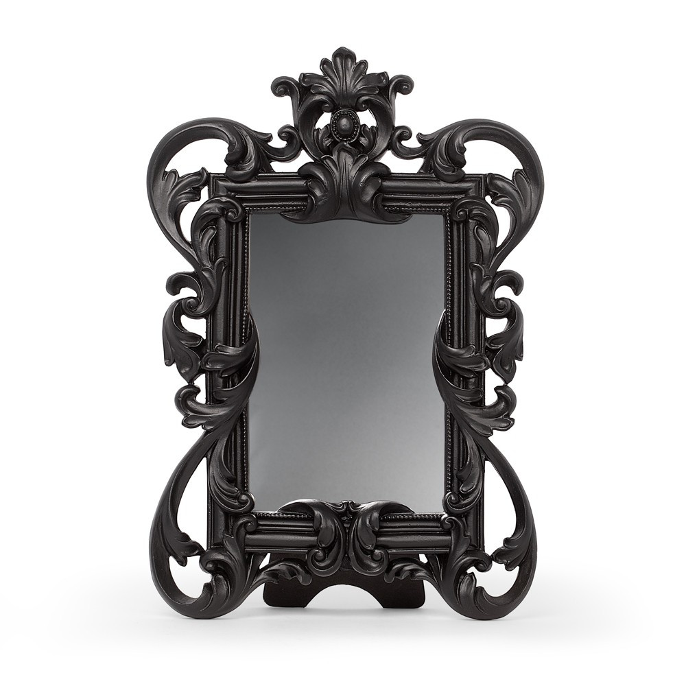 A Rococo-style decorative mirror with elaborate baroque flourishes and sweeping curves. Designed to stand as a bold gothic statement piece, its intricate resin frame and dark finish evoke antique grandeur with a shadowy edge. Ideal for dressing tables, shelves, or feature displays, this mirror blends romance with dramatic styling. • Ornate Rococo mirror with dramatic baroque detailing • Decorative resin frame with flowing gothic curves • Ideal for dressing tables, shelves, or feature displays • Compact mirror perfect for adding vintage elegance • Deep-toned finish enhances dark interior styling • A statement piece for gothic and romantic home decor • Free-standing or wall hung, suitable for home decor displays