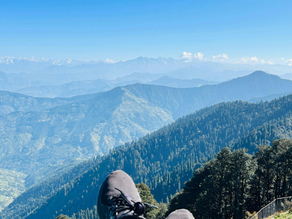 Traveler relaxing with feet up overlooking layered mountain views, representing slow and intentional travel. 