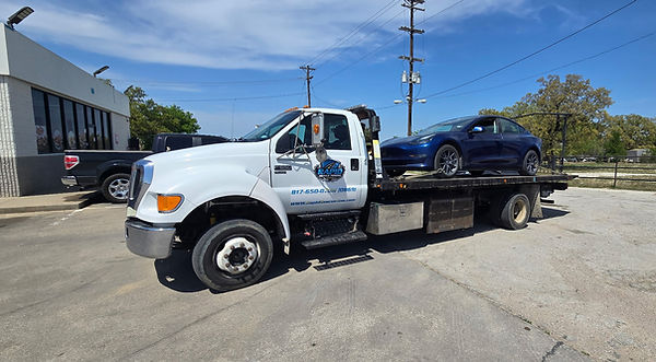 Tesla vehicle loaded on a Rapid Rescue Towing rollback truck for transport