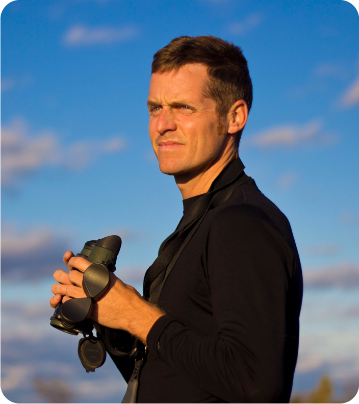 portrait of caleb holding binoculars overlooking a scene outside