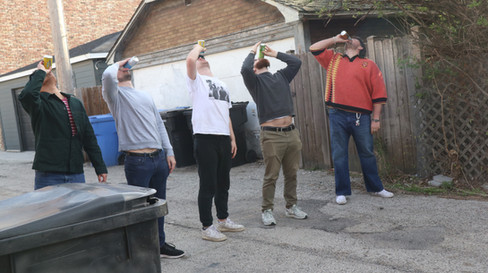 Five men in an alleyway chug beers