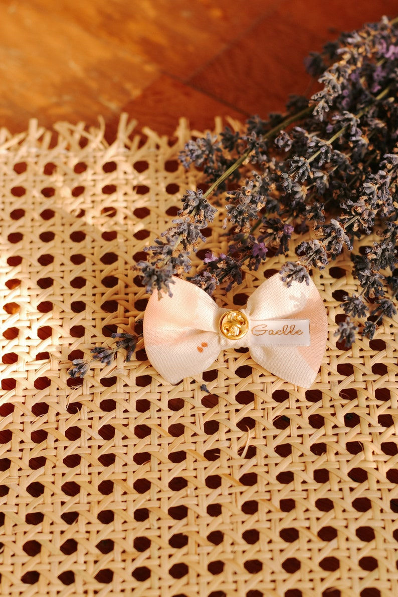 Miniature : Pin's noeud blanc tâche marron glacé, bleu et rose poudré