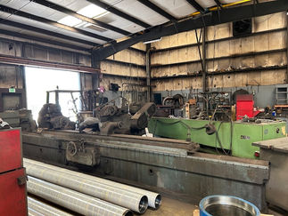 Large cylindrical grinder with finished rolls beside it.