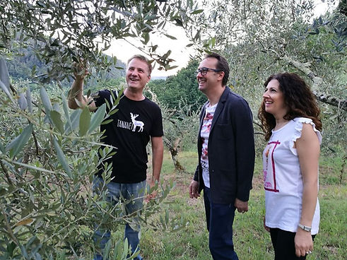 Visitors exploring different olive tree varieties during an extra virgin olive oil experience at Tananei olive grove in Tuscany