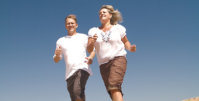 middle-aged couple running on beach, bac