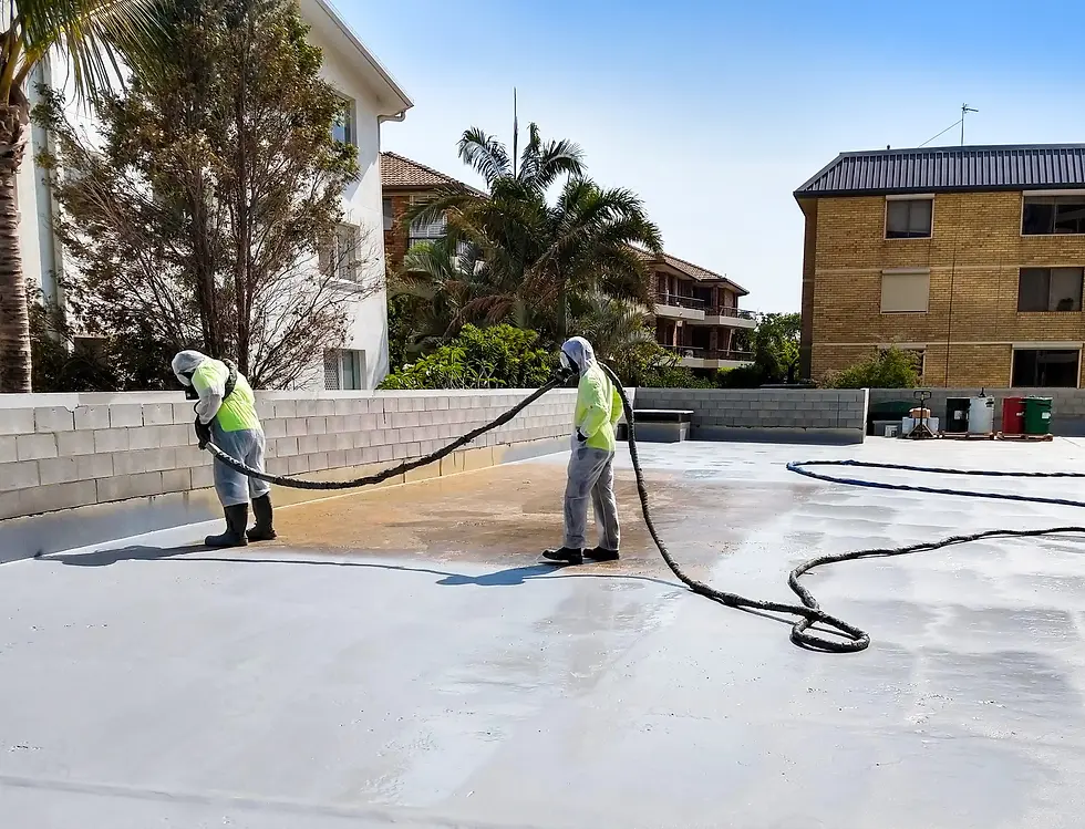 Workers applying a protective sealer to a large concrete surface at a commercial property.