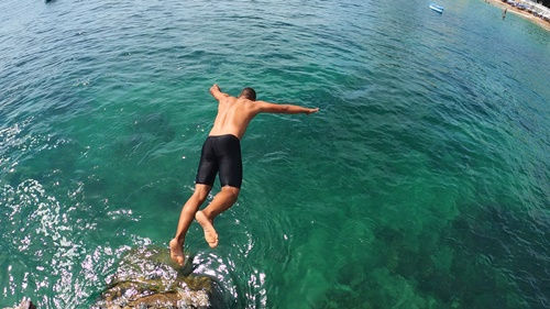 Jovem mergulhando nas águas cristalinas do Porto da Barra