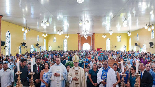 multidao na igreja e paroquia e quatro velas em primeiro plano