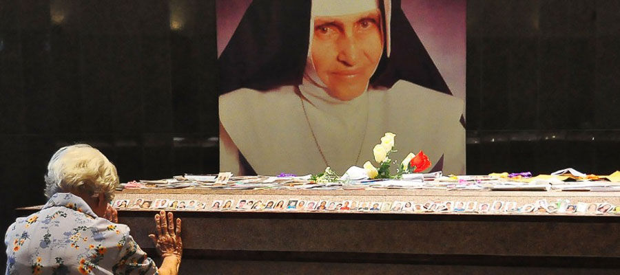 senhora ajoelhada rezando para irma dulce e flores no altar