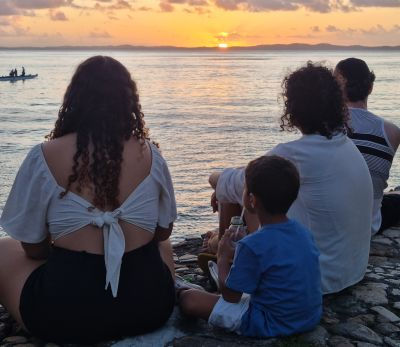 criança e sua familia curtindo pôr do sol
