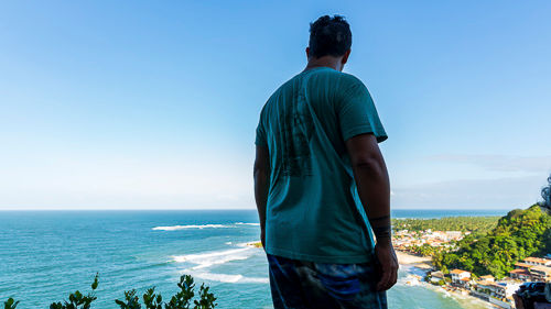 homem de costas olhando o mar de cima