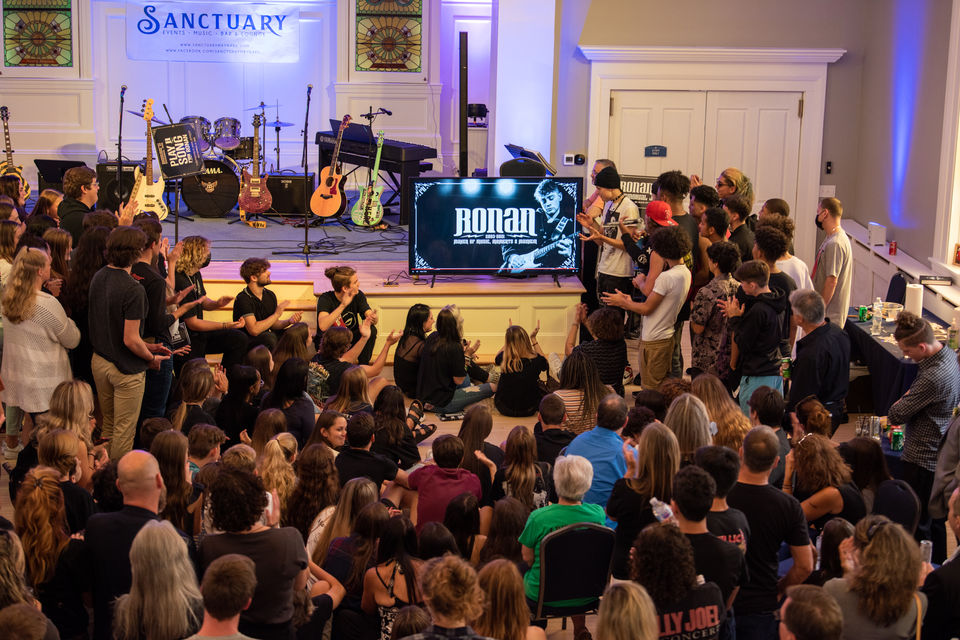 A crowd gathers to watch a memorial video.