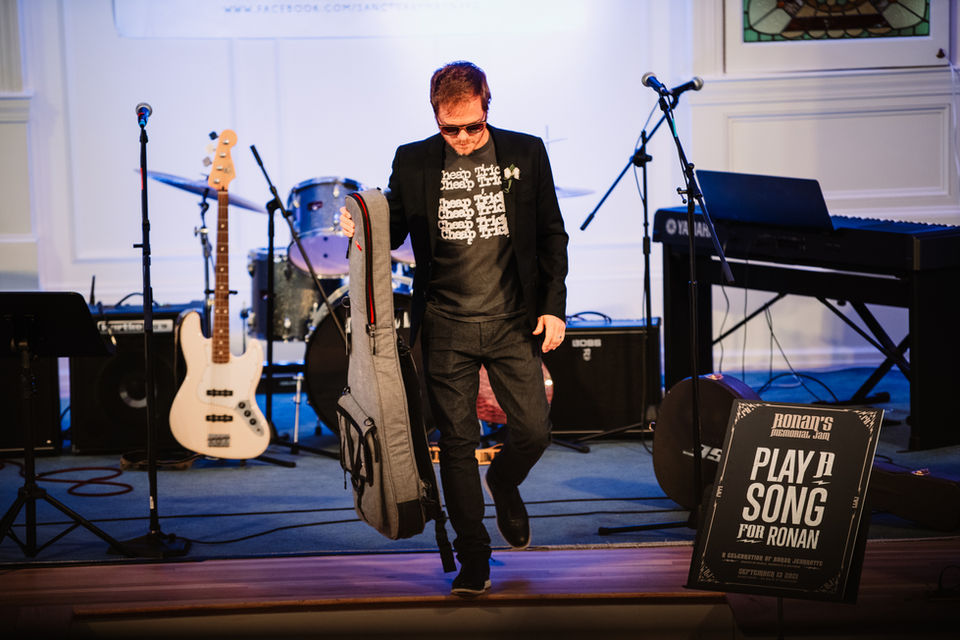 A musician with a guitar leaves the stage. 