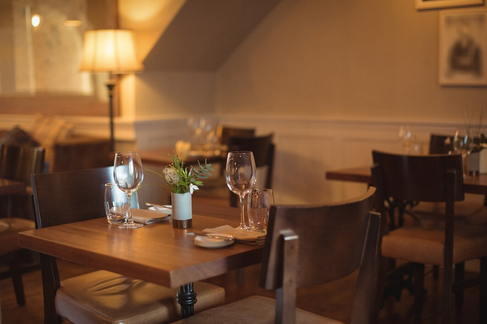 Modern restaurant interior with tables, chairs, and glassware set for dining experience.