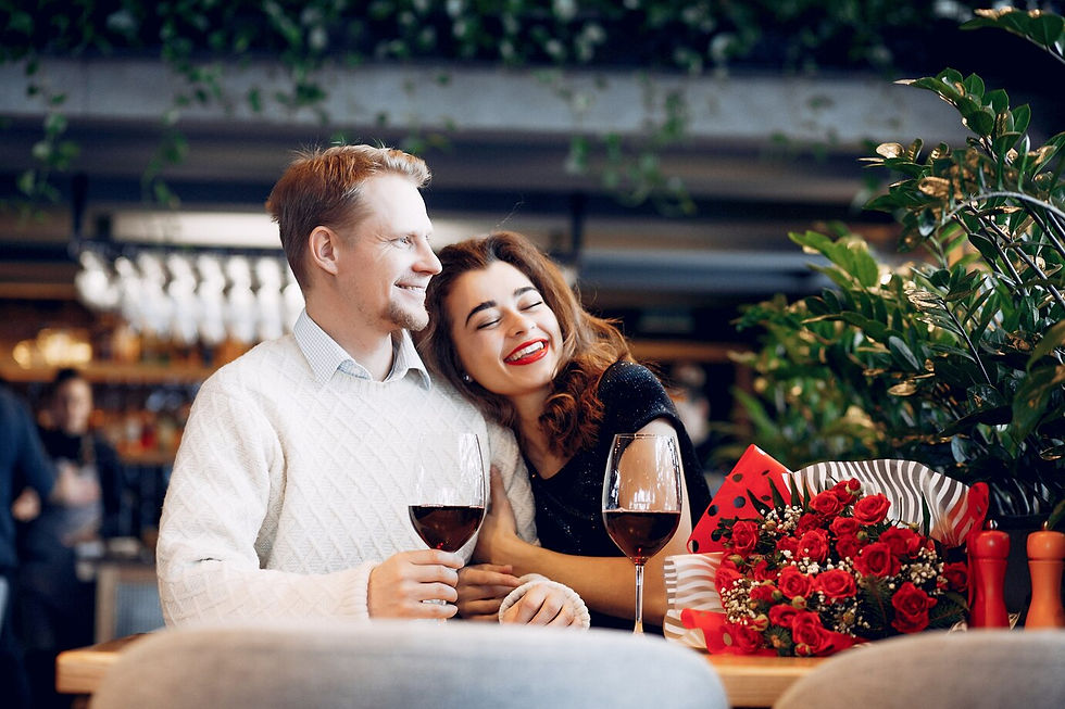 Couple on a date, toasting with wine, smiling, and roses on the table