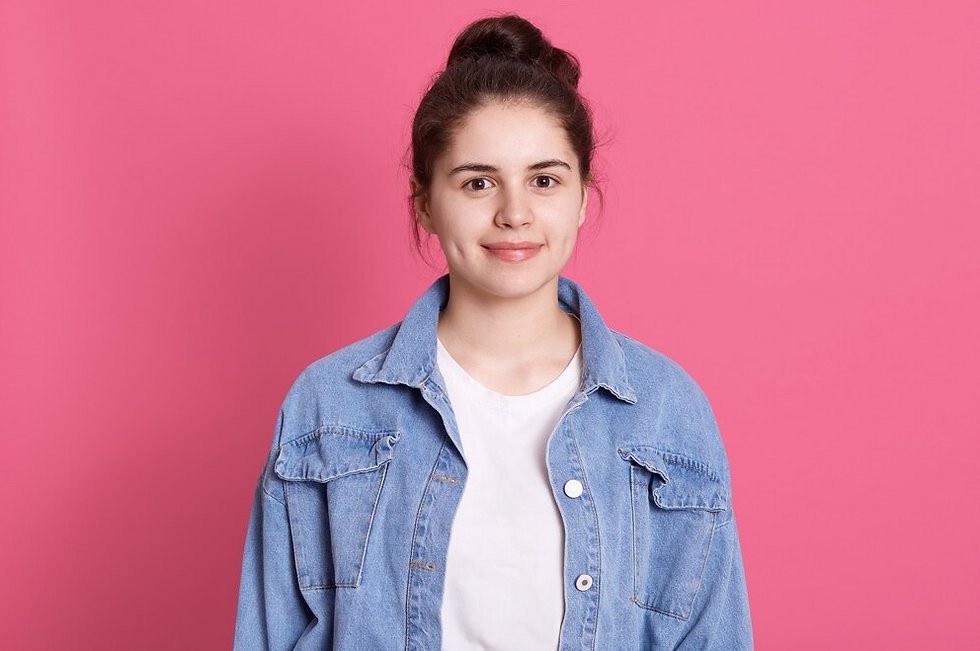 Smiling woman in denim jacket, pink background