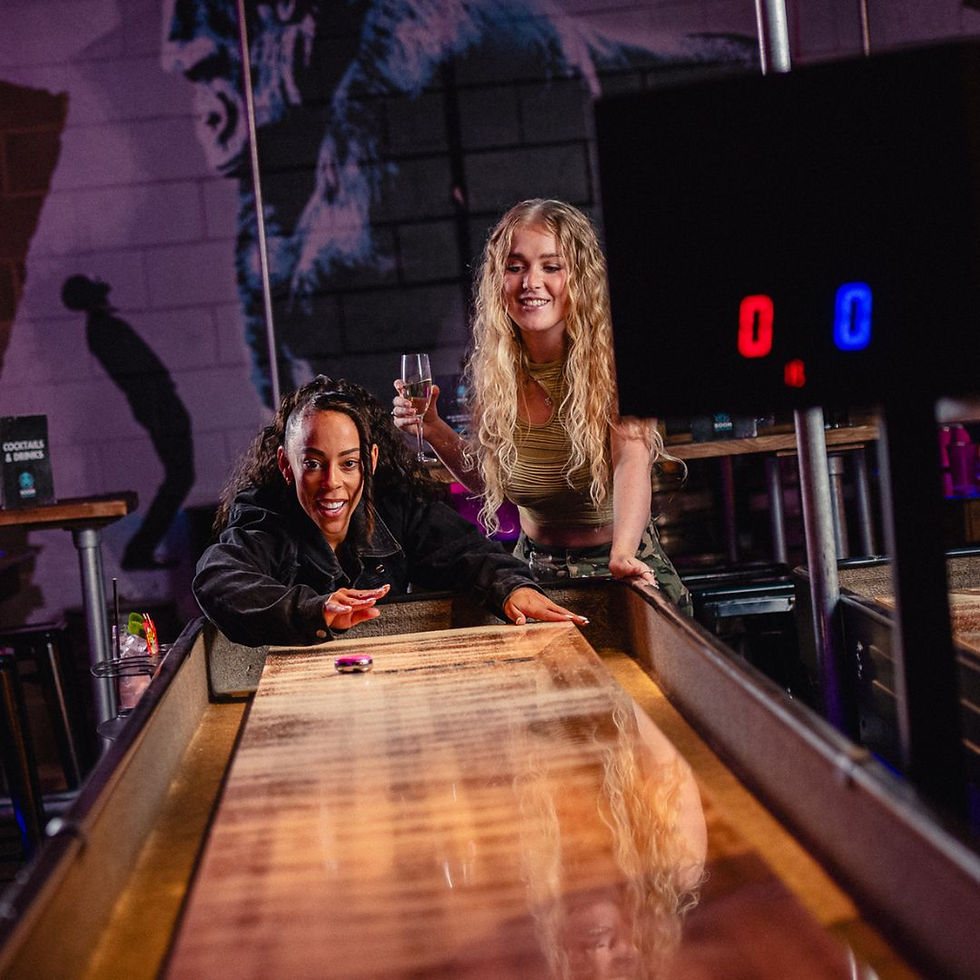 Twee vriendinnen spelen shuffleboard tijdens een avondje uit