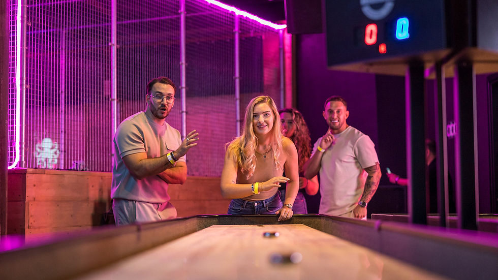Vriendengroep speelt shuffleboard onder kleurrijke neonverlichting