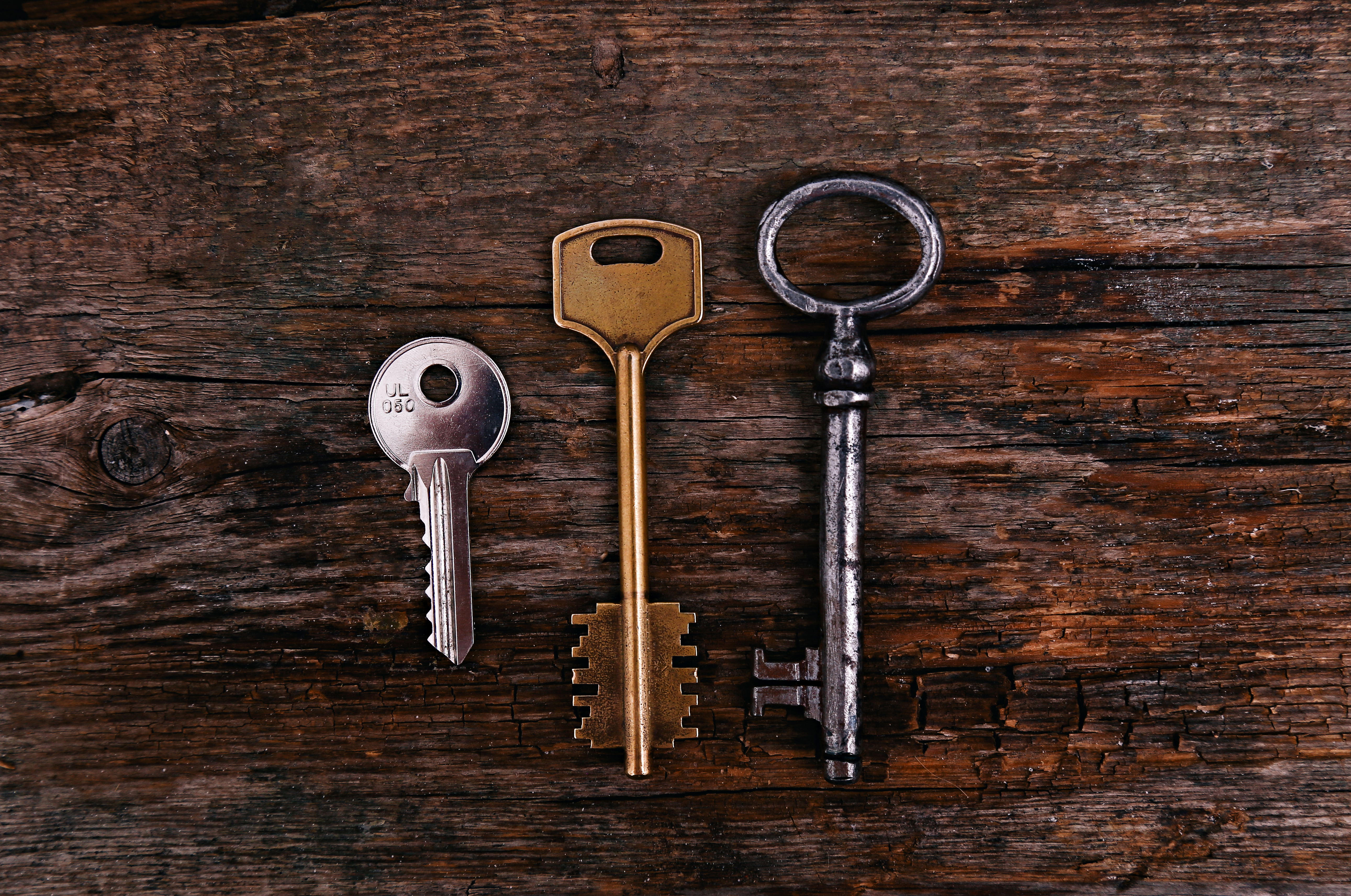 Three types of keys on a rustic wooden background representing Ace Locksmith LLC's commitment to high-quality locksmith servi