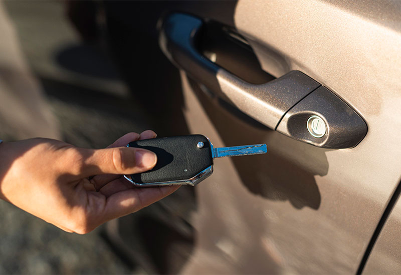 Car key being used near a vehicle door for unlocking.
