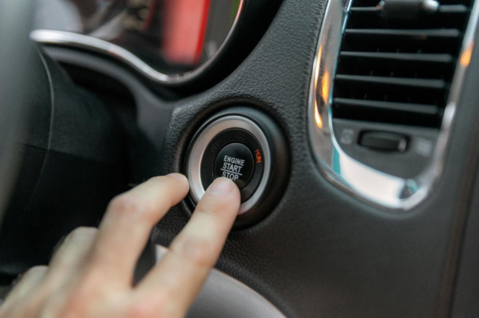 Person pushing Engine Start Stop button in car