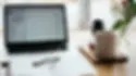 Laptop, notepad and coffee cup on desk, work from home environment.