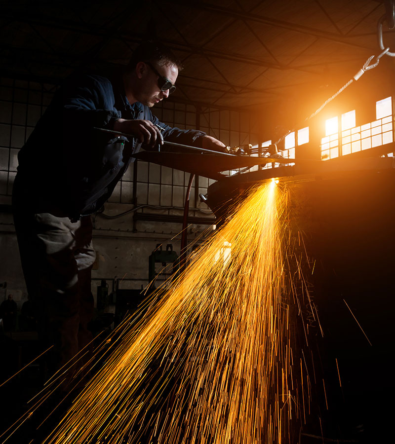 Welder cutting metal with bright sparks in an industrial setting
