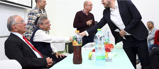 David Portowicz shaking hands with scholarship recepiant leaning over table