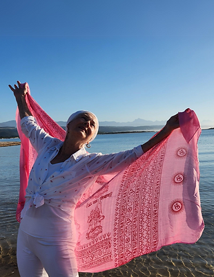 Kundalini Yoga teacher holding up a beautiful Indian printed pink scarf with the sunlight shining through