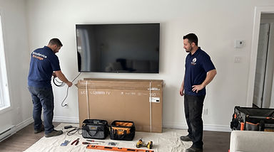Technicians completing a TV wall mount installation with tools and equipment arranged below the mounted television